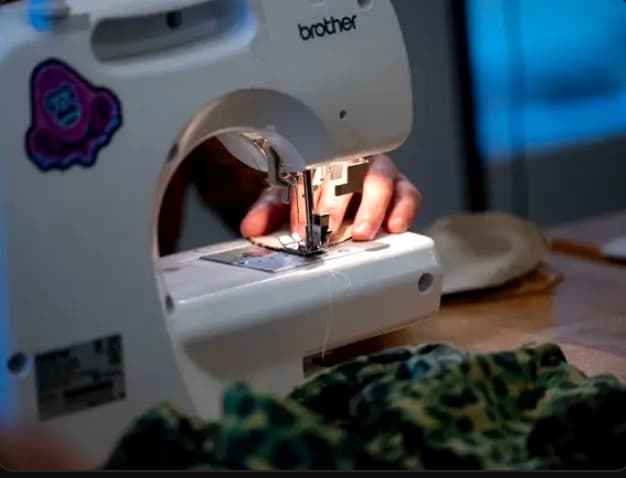 Brother sewing machine with an Ape Outfitters sticker — live apparel creation by Evan Brock
